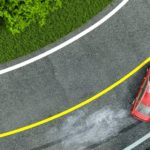 A red sedan is shown from a high angle speeding on a corner.