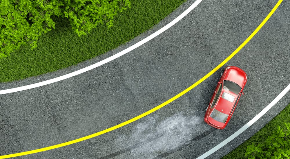 A red sedan is shown from a high angle speeding on a corner.