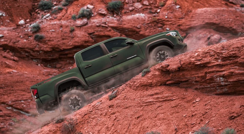A dark green 2021 Toyota Tacoma TRD is shown driving up a dirt path.