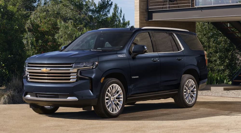 A blue 2023 Chevy Tahoe is shown parked in front of a house.