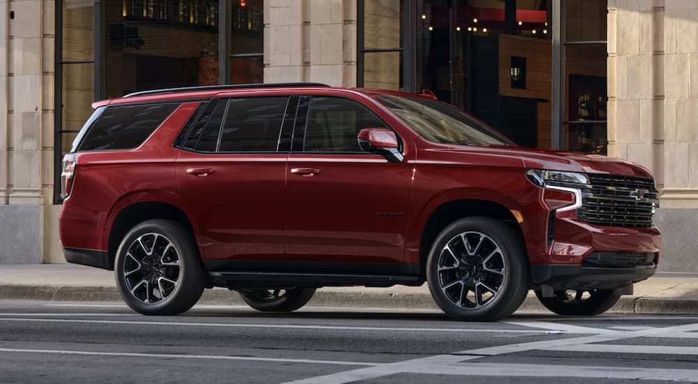 A red 2023 Chevy Tahoe for sale is shown driving on a city street.