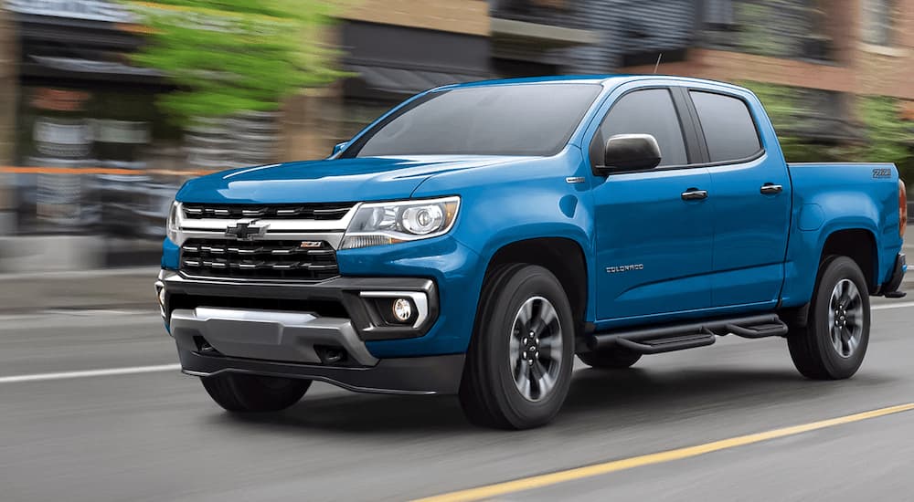A blue 2022 Chevy Colorado Z71 is shown driving on a city street after leaving a Chevy truck dealership.