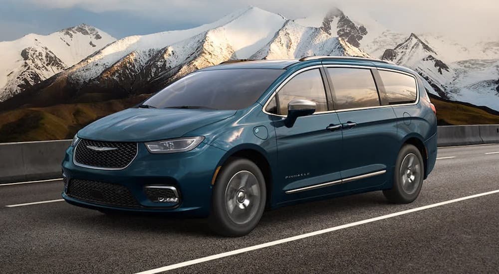 A blue 2021 Chrysler Pacifica Hybrid is shown from the side driving on an open road.