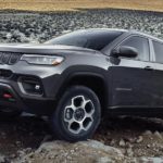 A grey 2022 Jeep Compass Trailhawk is shown from the side parked on a rocky road.