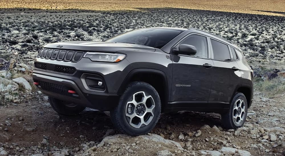 A grey 2022 Jeep Compass Trailhawk is shown from the side parked on a rocky road.