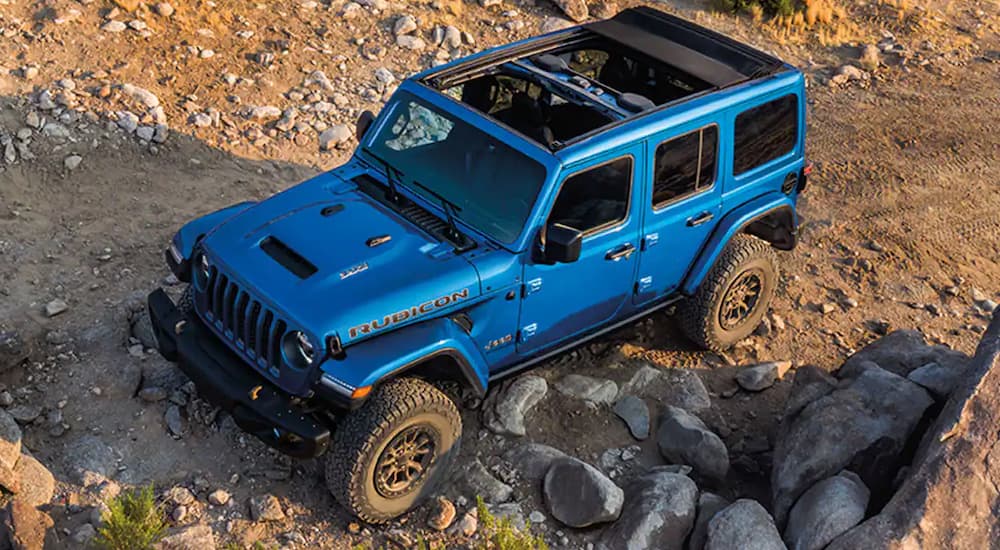 A blue 2022 Jeep Wrangler Rubicon 392 is shown on a rocky path after leaving a Jeep Wrangler dealer.