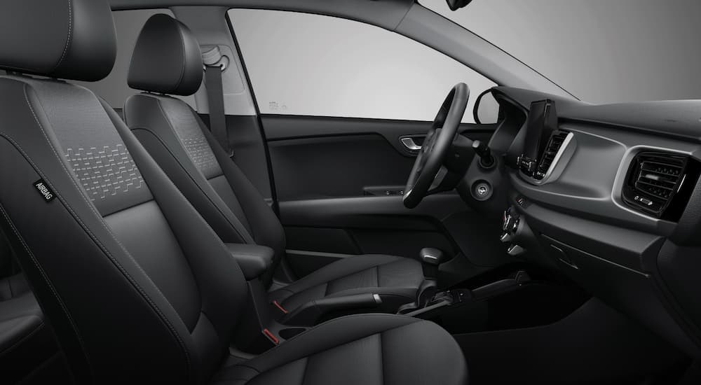 The grey interior of a 2023 Kia Rio shows the front seats.