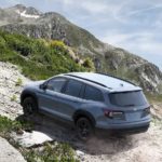 A grey 2022 Honda Pilot Trailsport is shown from the rear while going up a rocky trail.