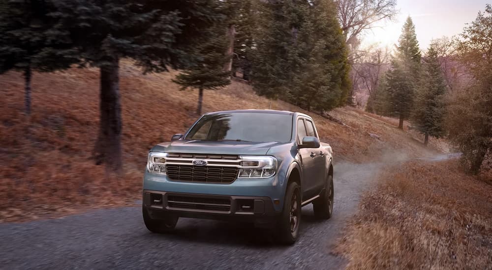 A blue 2022 Ford Maverick is shown driving up a gravel road.