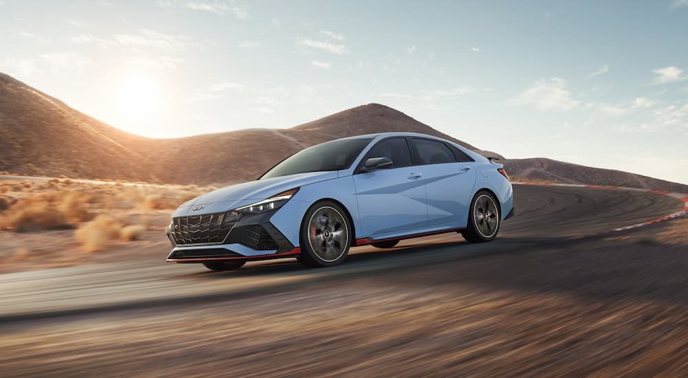 A light blue 2022 Hyundai Elantra N is shown rounding a corner on a race track.