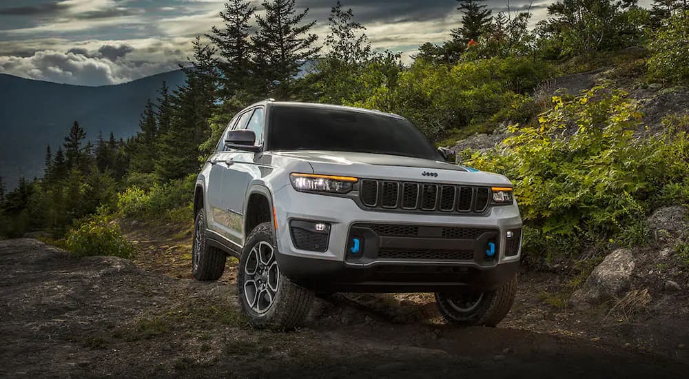 A grey 2022 Jeep Grand Cherokee 4xe is shown driving on a mountain trail.