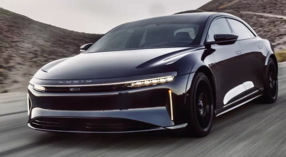 A black 2022 Lucid Air is shown driving on an open road.