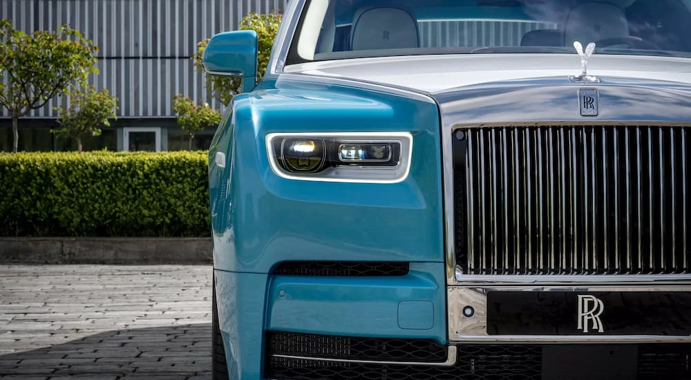 A close up shows the passenger side headlight on a aqua 2022 Rolls-Royce Phantom.