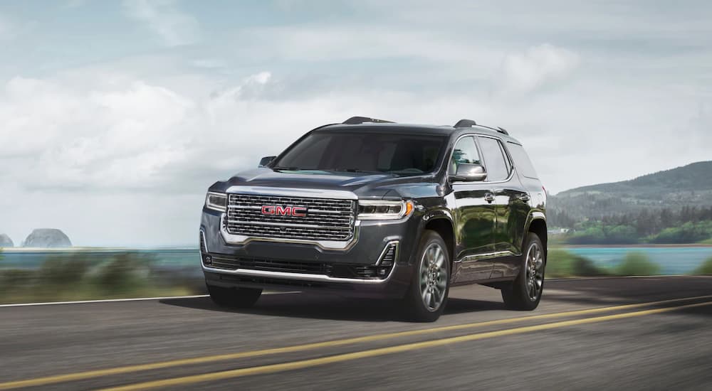 A black 2020 GMC Acadia is shown driving on an open road.