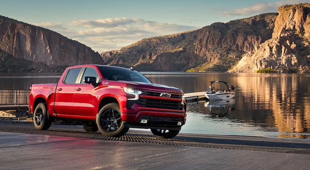 A red 2022 Chevy Silverado 1500 RST is shown parked next to a lake boat launch.