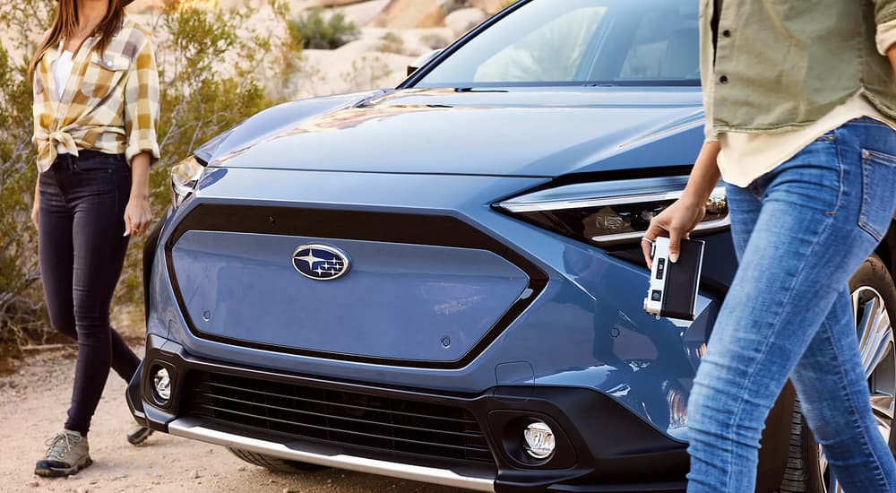 Two women are shown walking by the front of a blue 2023 Subaru Solterra after leaving a Subaru dealer.