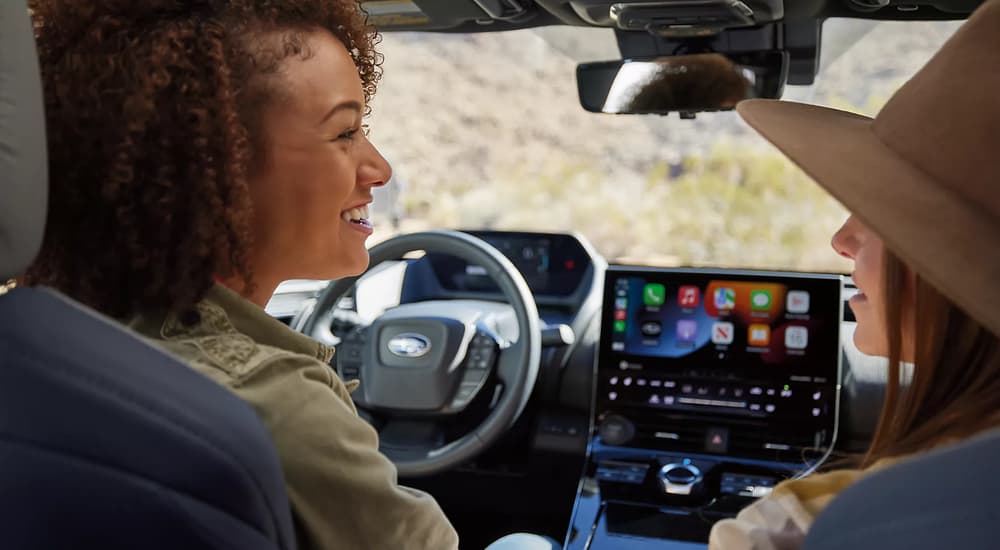 Two women are shown chatting in the front seats of a 2023 Subaru Solterra.