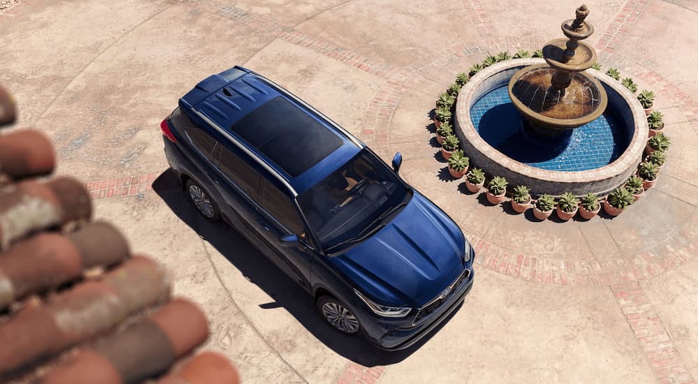A red 2023 Toyota Highlander is shown from a high angle next to a water fountain. 