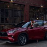 A red 2023 Toyota Highlander for sale near you is shown on the side of a city street.