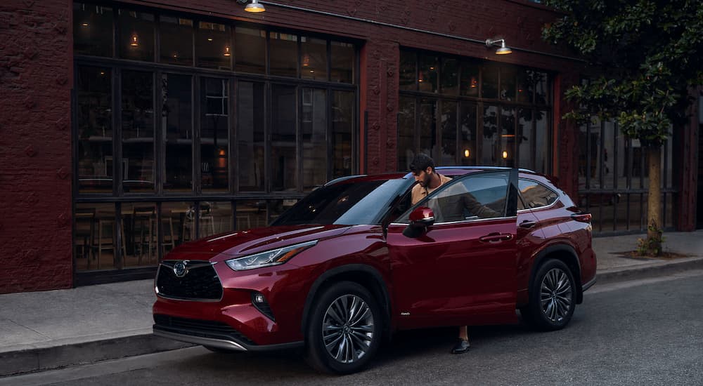 A red 2023 Toyota Highlander for sale near you is shown on the side of a city street.