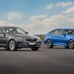 A grey and a blue 2016 used BMW 3 Series for sale are shown in an empty lot.