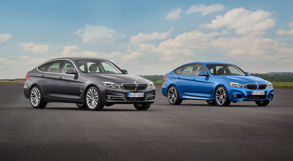 A grey and a blue 2016 used BMW 3 Series for sale are shown in an empty lot.