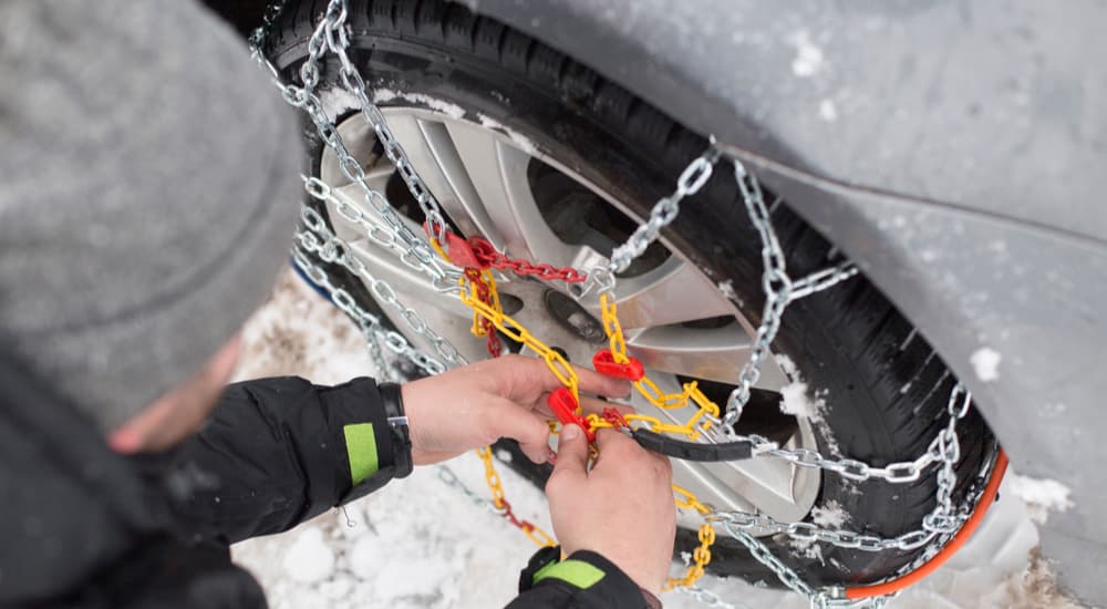 A person is shown adjusting the chains on their tires.
