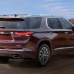 A maroon 2022 Chevy Traverse is shown from the rear driving on an open road.