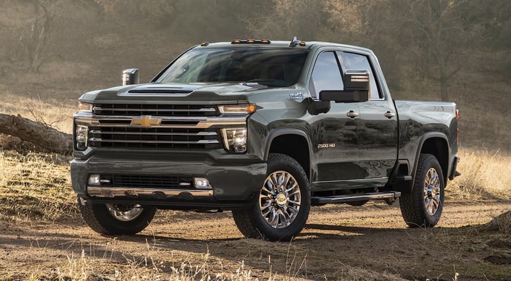 A green 2022 Chevy Silverado 2500 HD is shown parked on a dirt road after leaving a certified work truck dealer.