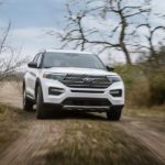 A white 2023 Ford Explorer King Ranch is shown from the front on a dirt trail.