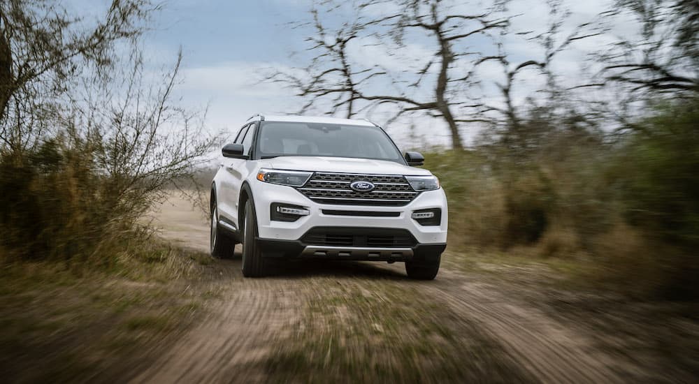 A white 2023 Ford Explorer King Ranch is shown from the front on a dirt trail.