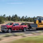 A red 2022 Chevy Silverado 3500HD is shown from the side while towing a bulldozer.