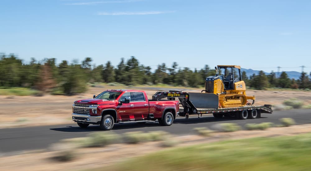 A red 2022 Chevy Silverado 3500HD is shown from the side while towing a bulldozer.