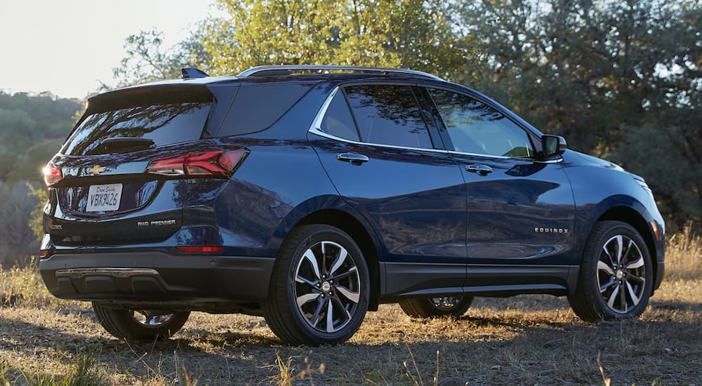 A blue 2023 Chevy Equinox is shown from the side parked in a field.