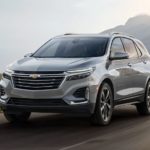 A grey 2023 Chevy Equinox is shown driving on an open road during a 2023 Chevy Equinox vs 2023 Nissan Rogue comparison.