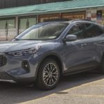 A grey 2023 Ford Escape is shown from the side parked in front of a restaurant.