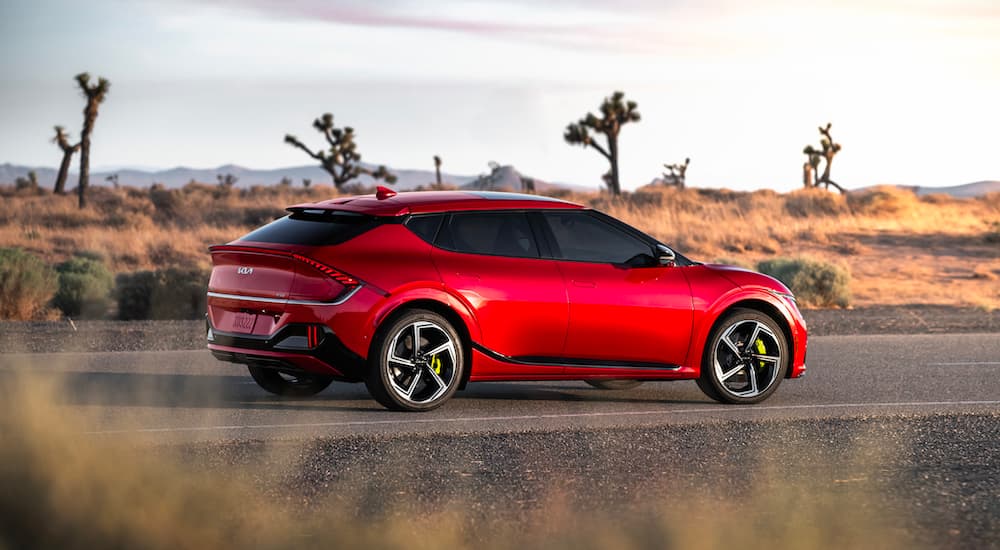 A red 2023 Kia EV6 GT is shown from the side on a desert road.