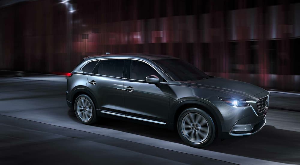 A grey 2023 Mazda CX-9 is shown driving on concrete.