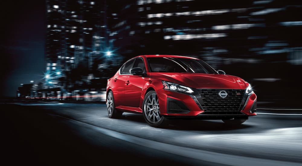 A red 2023 Nissan Altima SR is shown driving on a city street.