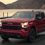 A red 2022 Chevy Silverado 1500 is shown from the front parked in front of a lake.