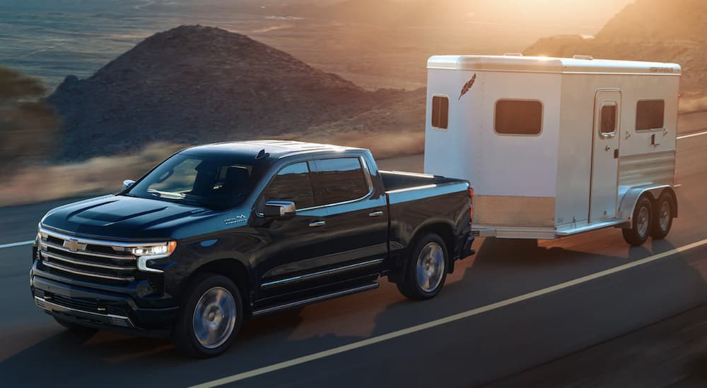 A black 2022 Chevy Silverado 1500 is shown towing trailer on an open road.