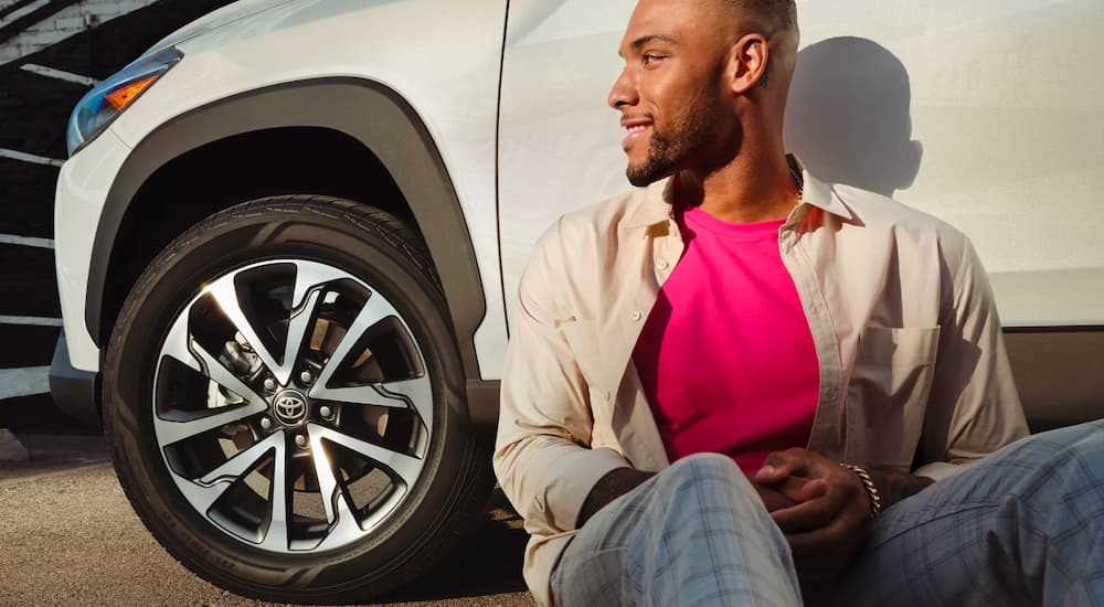 A person is shown leaning against a white 2022 Toyota Corolla Cross XLE.