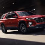 A red 2023 Chevy Traverse RS is shown from the side driving on an open road.