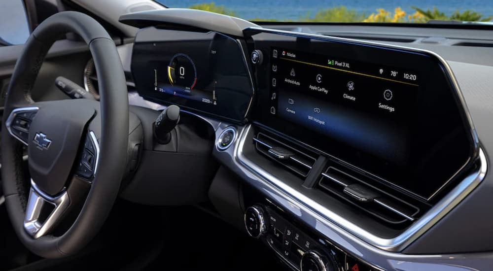 The black interior of a 2024 Chevy Trax shows the steering wheel and infotainment screen.