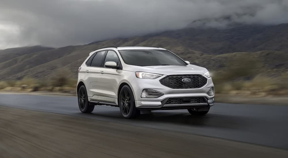 A white 2023 Ford Edge is shown driving on an open road.