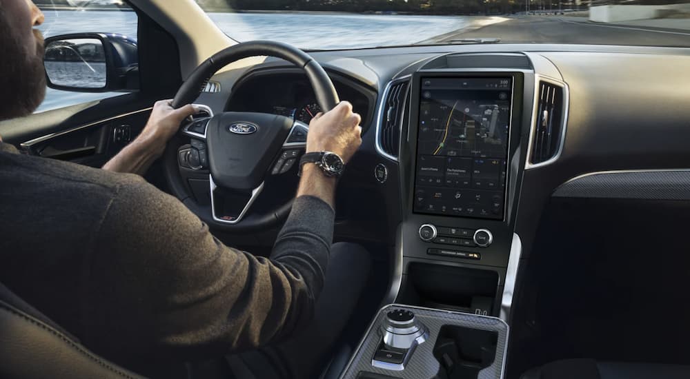 The black interior of a 2023 Ford Edge shows the steering wheel and infotainment screen.