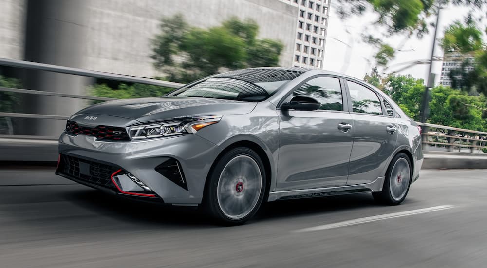A silver 2023 Kia Forte GT is shown driving on a city street.