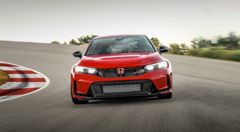 A red 2023 Honda Civic Type R is shown from the front while driving on a racetrack.