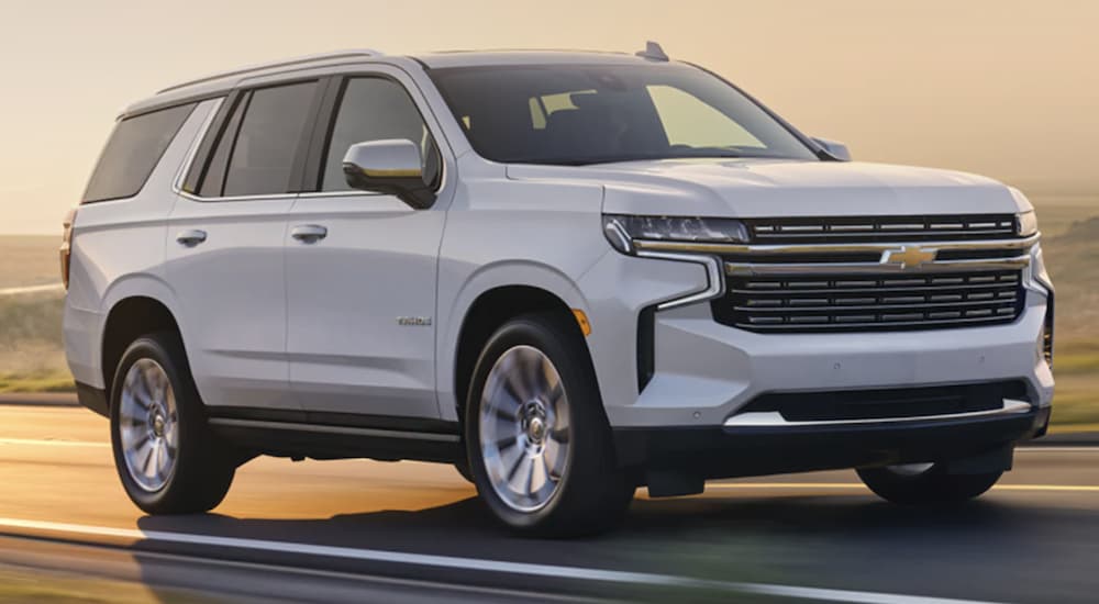 A white 2023 Chevy Tahoe is shown from the front driving on an open road.