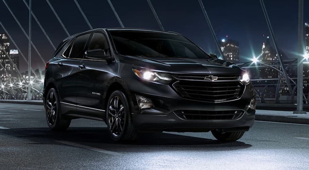 A black 2020 Chevy Equinox is shown from the front driving at night.